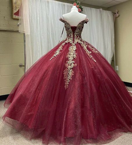 off-the-shoulder quinceañera ball gown in deep burgundy red tulle, decorated with intricate gold floral lace appliques and a sparkling beaded bodice