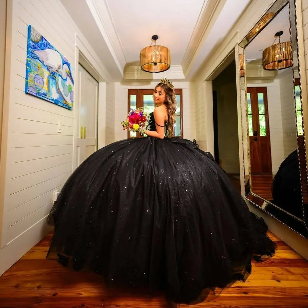 black ball gown with sparkly details and holding a colorful bouquet of flowers.