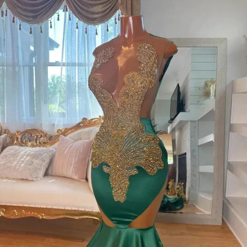 A formal gown emerald green satin with extensive gold beaded and sequined embellishments across the bodice and hips, and a low cut with side cutouts.