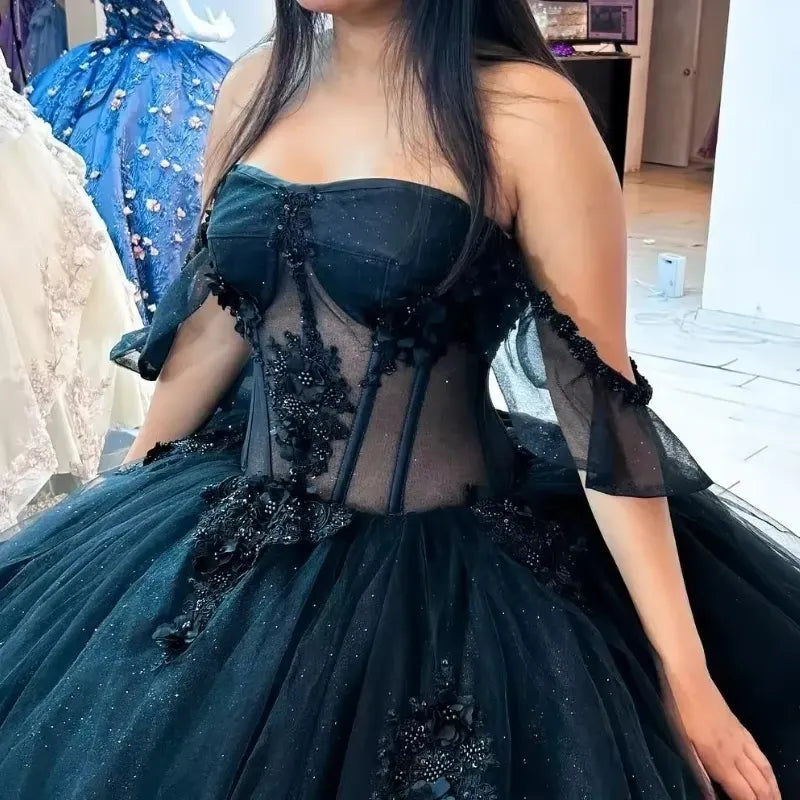 dramatic black ball gown with a strapless sweetheart bodice, sheer mesh panels, floral appliqué, and a voluminous tulle skirt
