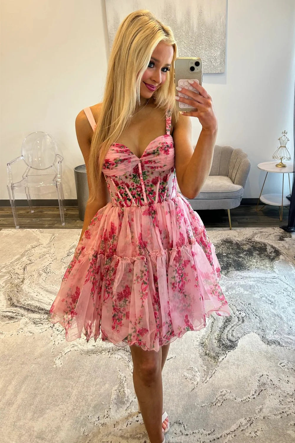Woman wearing a pink floral hoco dress in an indoor setting.